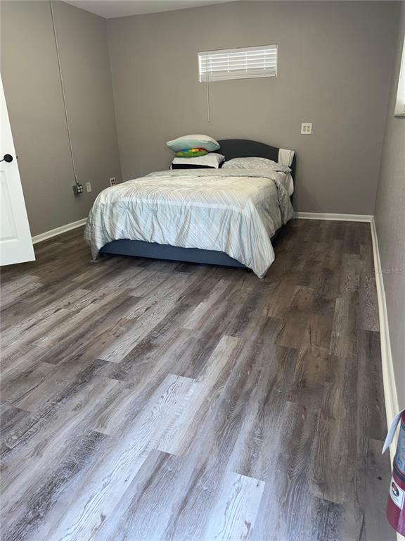 A bedroom with gray walls, wood-look flooring, and a bed centered against the back wall — 5950 HIGH STREET, NEW PORT RICHEY, FL
