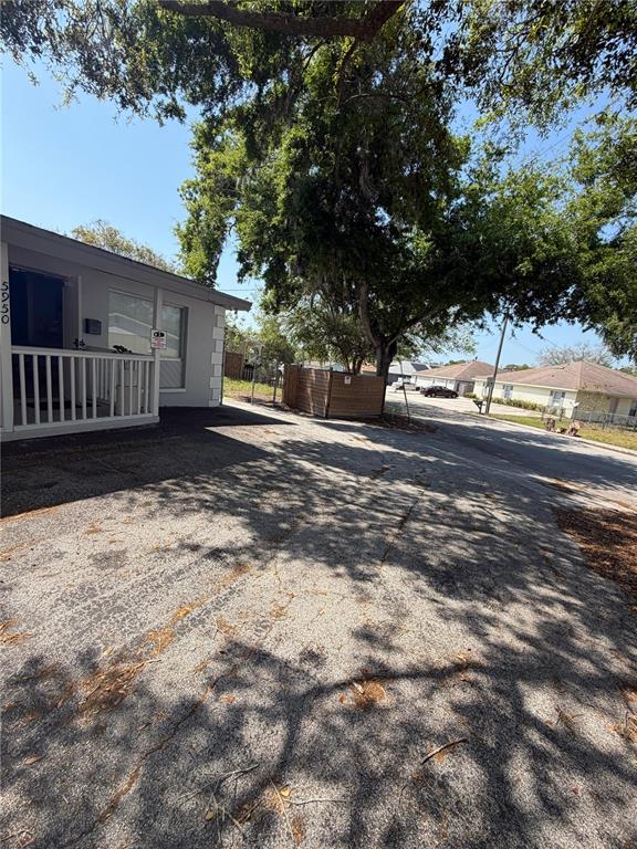 A paved driveway leads to the side entrance of a house with a white porch — 5950 HIGH STREET, NEW PORT RICHEY, FL