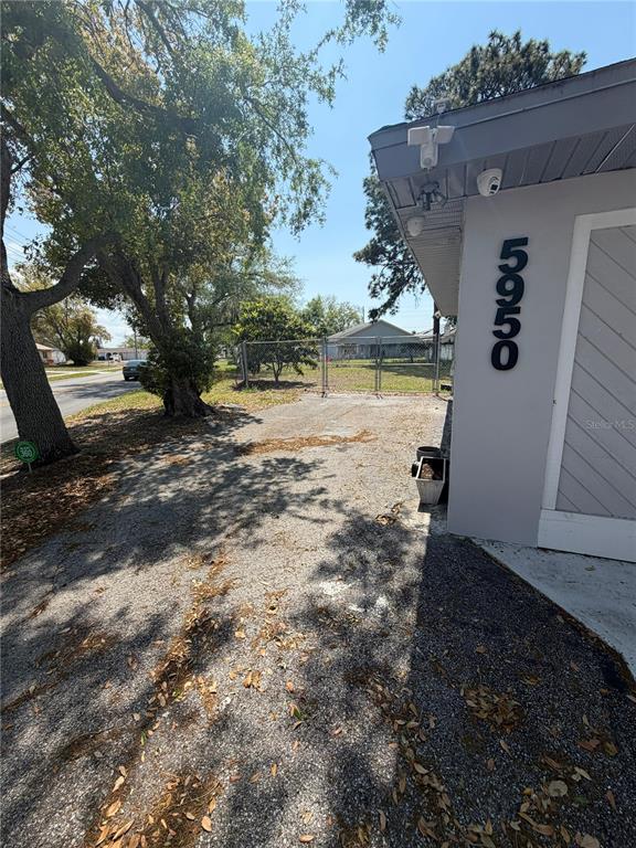 An exterior view shows a gravel driveway beside a building with the number 5950 — 5950 HIGH STREET, NEW PORT RICHEY, FL