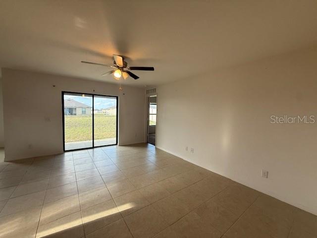 An empty room with light-colored tile flooring, a ceiling fan, and sliding glass patio doors — 1884 AMBER SWEET CIRCLE, DUNDEE, FL