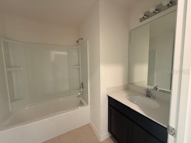 A bathroom features a white bathtub-shower combination, a dark vanity with a sink, and mirror — 1884 AMBER SWEET CIRCLE, DUNDEE, FL