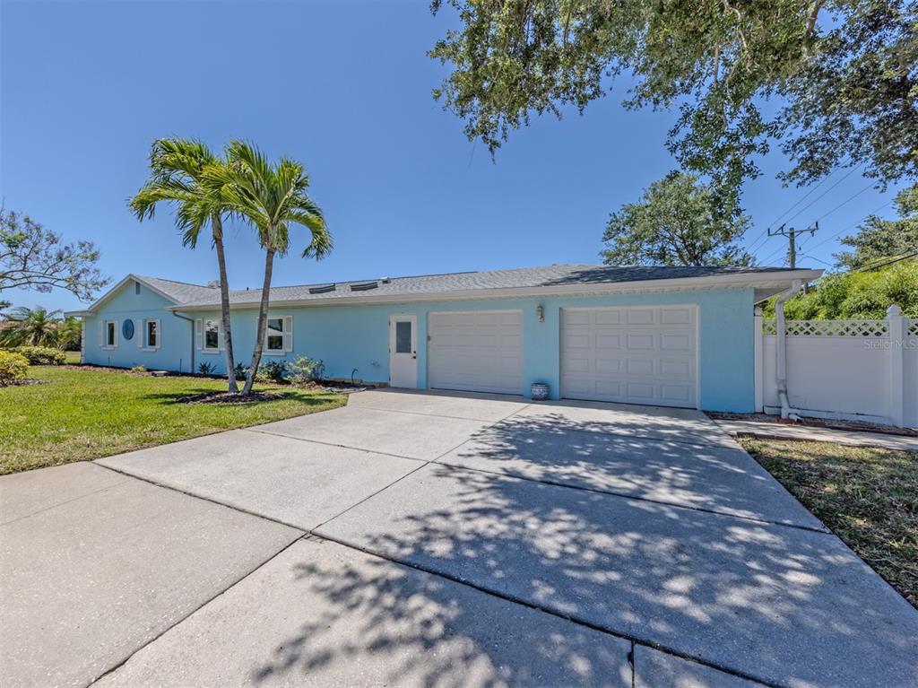 A light blue single-story house features a two-car garage, a concrete driveway, and palm trees — 500 ALHAMBRA ROAD, VENICE, FL