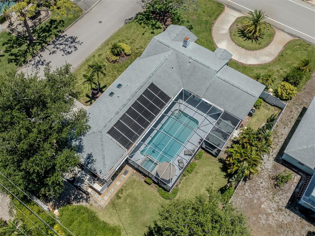 An aerial view shows a house with a shingled roof, solar panels, and a screened pool — 500 ALHAMBRA ROAD, VENICE, FL