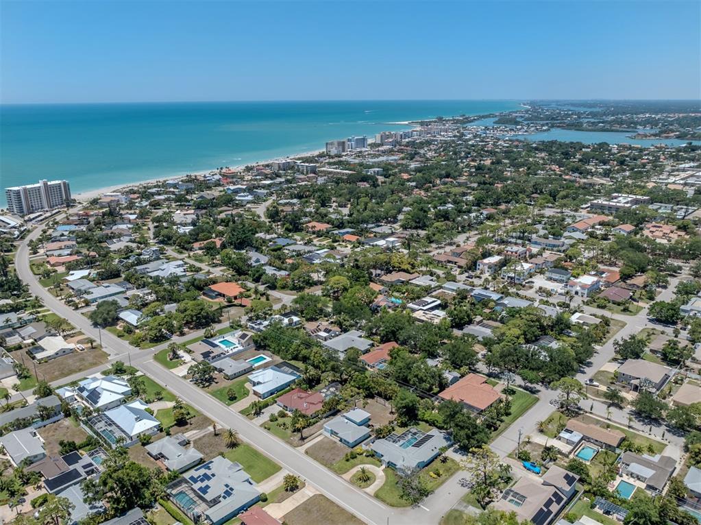 An aerial view shows a coastal neighborhood with houses, swimming pools, and the ocean beyond — 500 ALHAMBRA ROAD, VENICE, FL