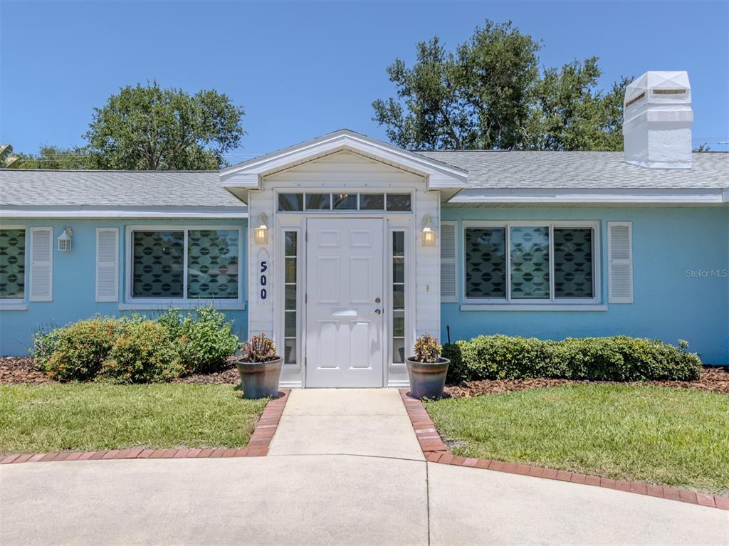 A light blue house features a white front door, a brick-bordered walkway, and a chimney — 500 ALHAMBRA ROAD, VENICE, FL