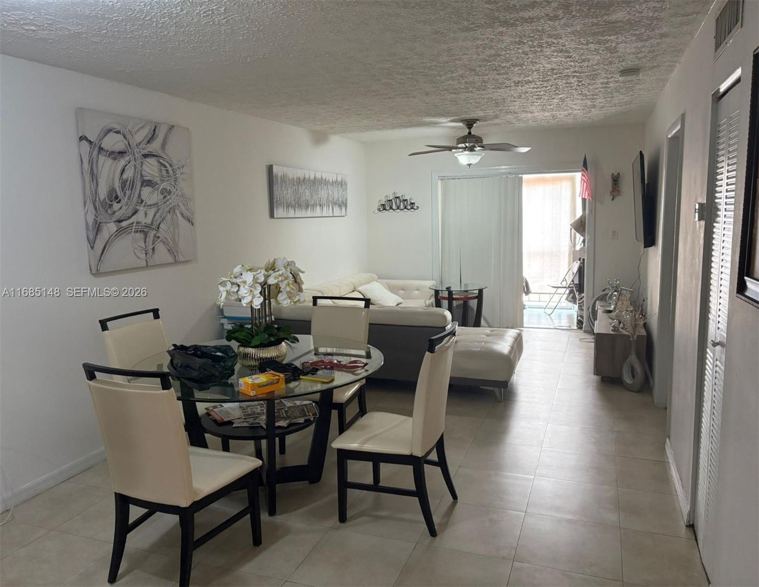 A living and dining area features tile floors, a glass table, and a white sofa — 6055 W 19th Ave # 318, Hialeah FL 33012, HIALEAH, FL