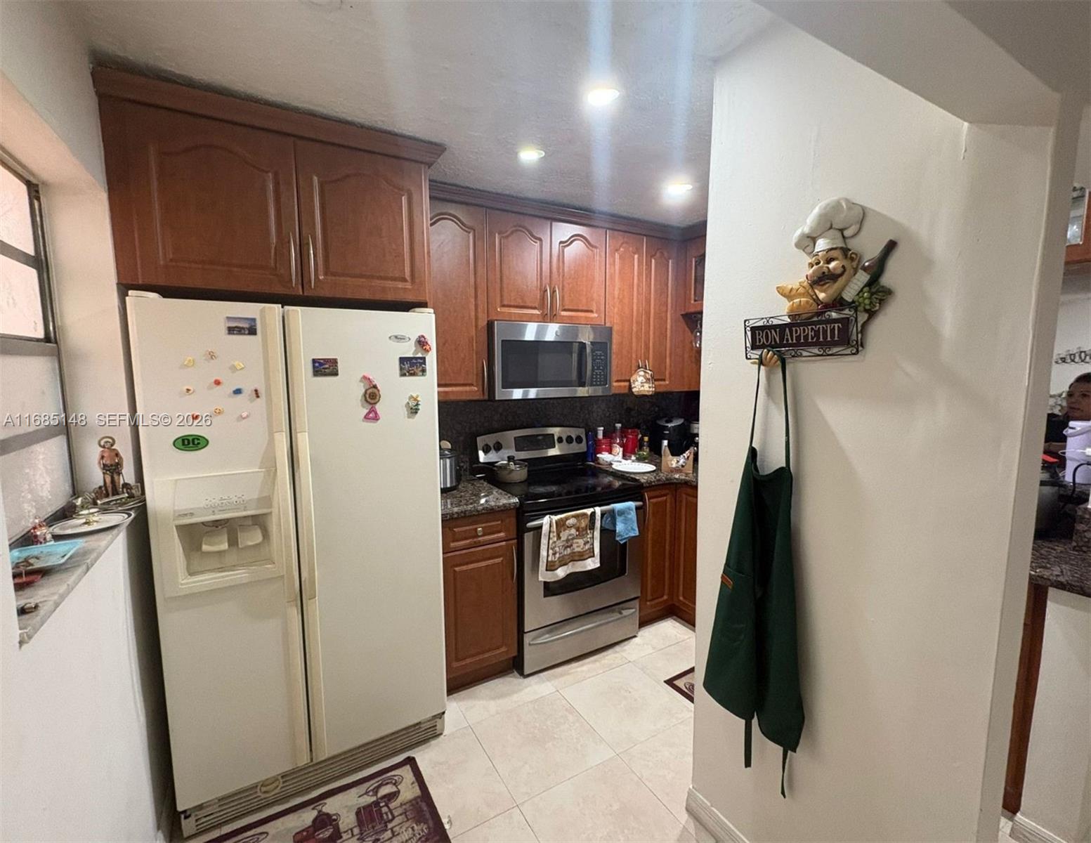 A kitchen features wood cabinets, stainless steel appliances, a white refrigerator, and tiled flooring — 6055 W 19th Ave # 318, Hialeah FL 33012, HIALEAH, FL