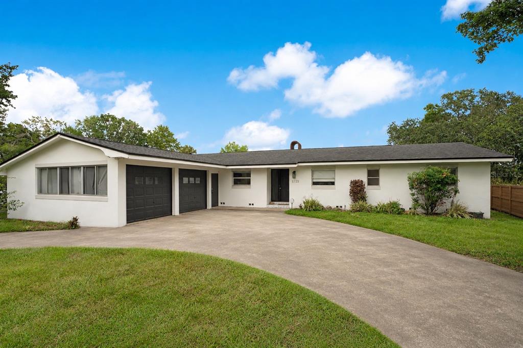A single-story white house with a dark roof, a two-car garage, and a concrete driveway — 5725 PADGETT CIRCLE, ORLANDO, FL
