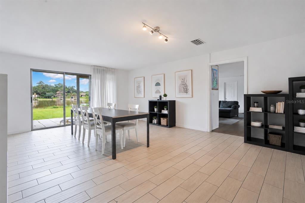 A dining room with tile floors, a dark table, and sliding doors overlooking a lake — 5725 PADGETT CIRCLE, ORLANDO, FL