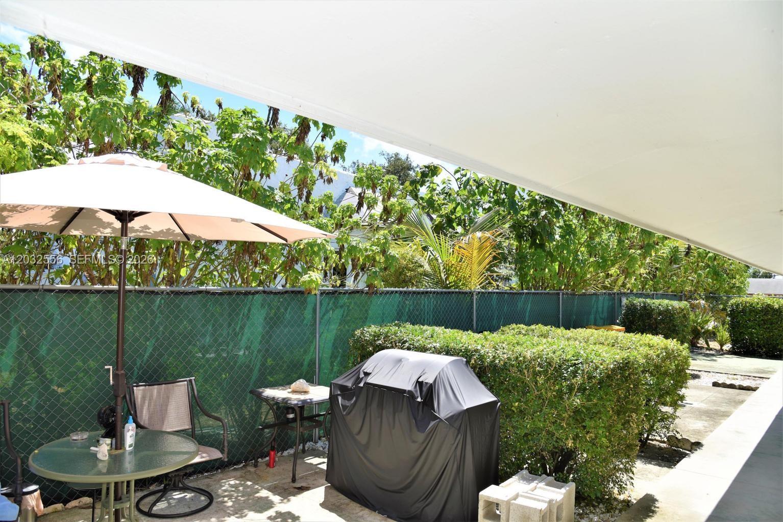 A patio features a covered seating area, a grill with a cover, and a chain-link fence — 1008 N 18  AVENUE, Lake Worth FL 33460, LAKE WORTH, FL