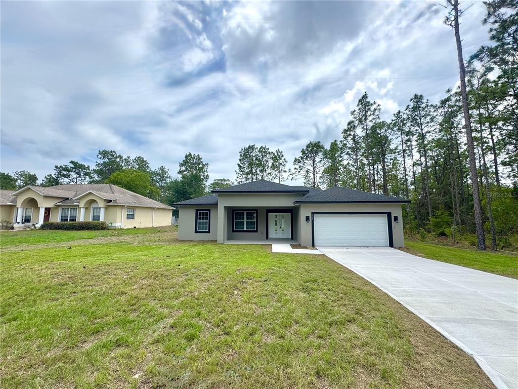 A modern single-story house with a two-car garage and a concrete driveway — 628 W HERONSBILL LANE, DUNNELLON, FL