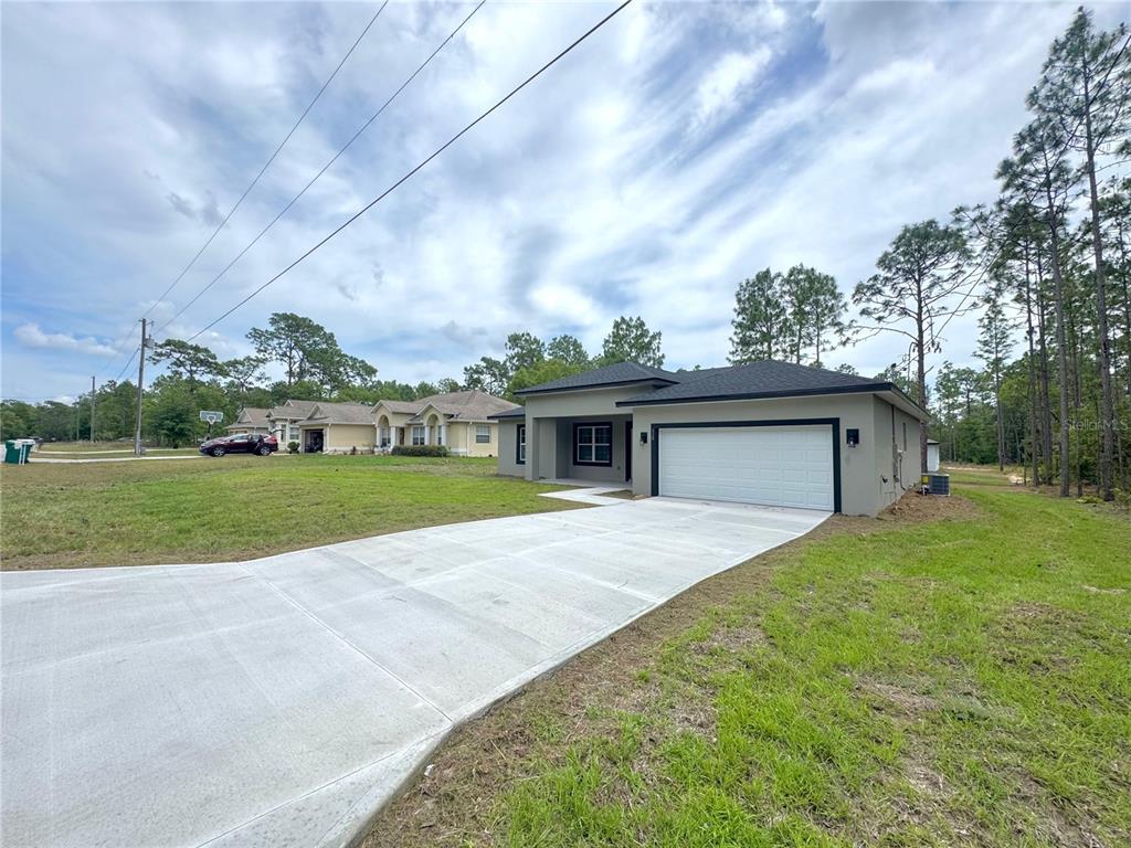 A modern single-story house with a white garage door and a concrete driveway — 628 W HERONSBILL LANE, DUNNELLON, FL