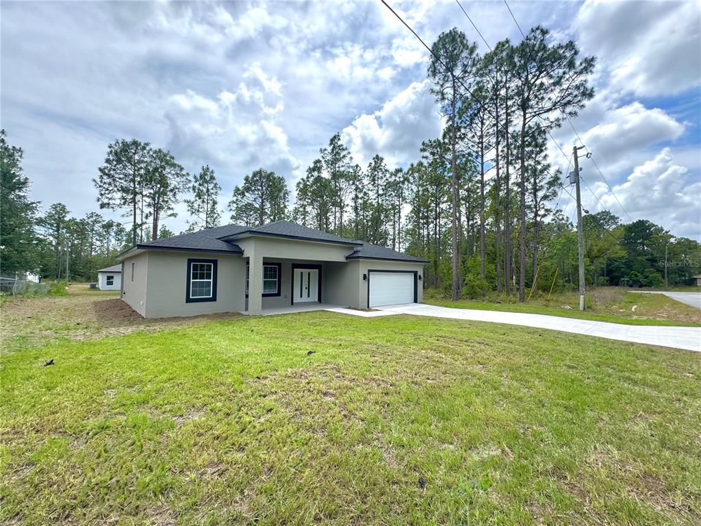 A newly constructed single-story house with a gray exterior, dark roof, and attached garage — 628 W HERONSBILL LANE, DUNNELLON, FL