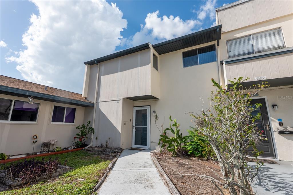 The exterior view shows a two-story townhouse with a concrete walkway leading to the entrance — 6860 WHITMAN COURT UNIT 32B, SARASOTA, FL