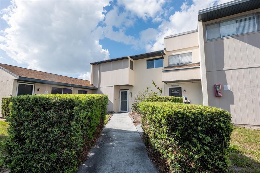 A concrete walkway leads to the entrance of a two-story townhouse with beige siding — 6860 WHITMAN COURT UNIT 32B, SARASOTA, FL