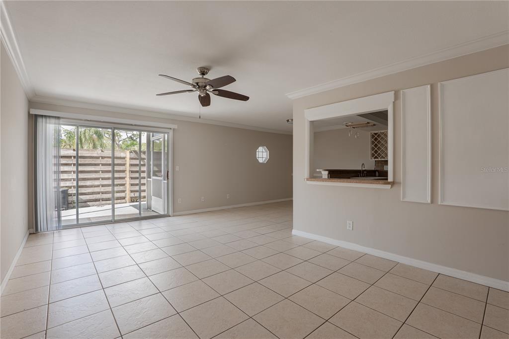 A living room with tile flooring, a ceiling fan, and a pass-through to the kitchen — 6860 WHITMAN COURT UNIT 32B, SARASOTA, FL