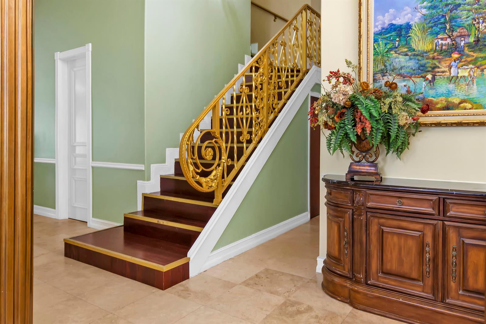 A foyer features a staircase with gold railings, dark wood steps, and a wooden cabinet — 12121 70th Place N, FL 33412, FL