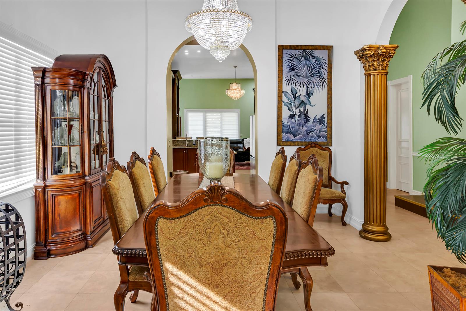 A formal dining room features a wooden table, upholstered chairs, a crystal chandelier, and columns — 12121 70th Place N, FL 33412, FL