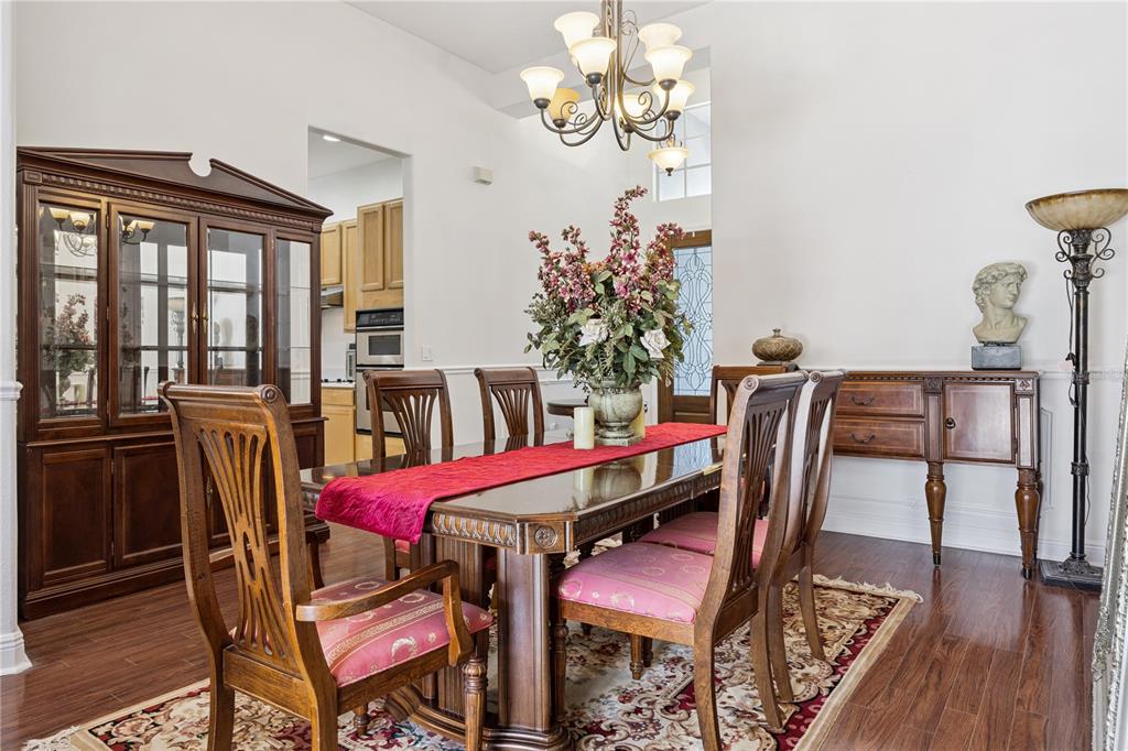 A formal dining room features a wooden table, chairs with pink cushions, and a chandelier — 710 REGINA CIRCLE, OAKLAND, FL