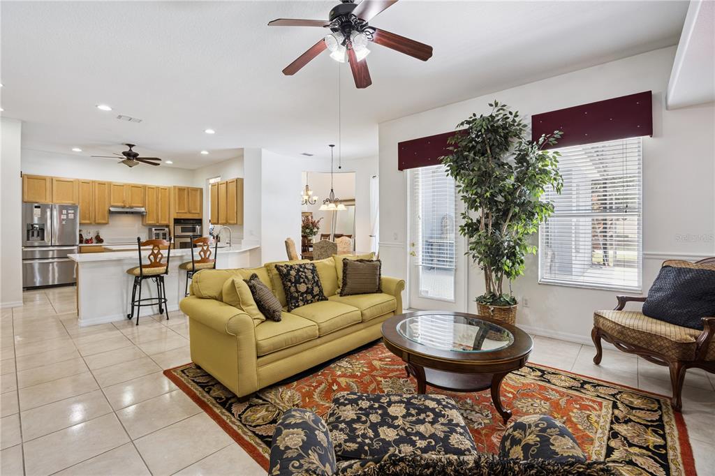 A living room with tile floors, a yellow sofa, and an open kitchen in the background — 710 REGINA CIRCLE, OAKLAND, FL