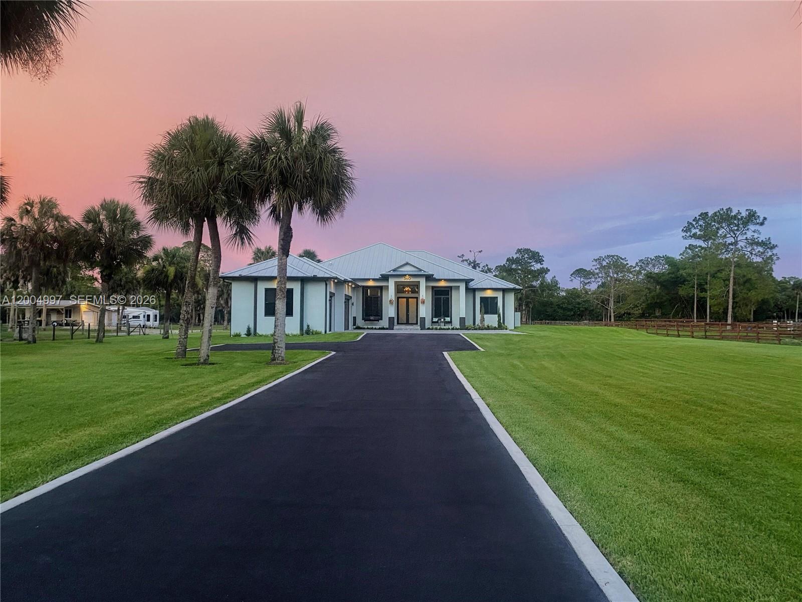A single-story house with a metal roof and paved driveway sits on a grassy lot — 360 13th St SW, Naples FL 34117, NAPLES, FL