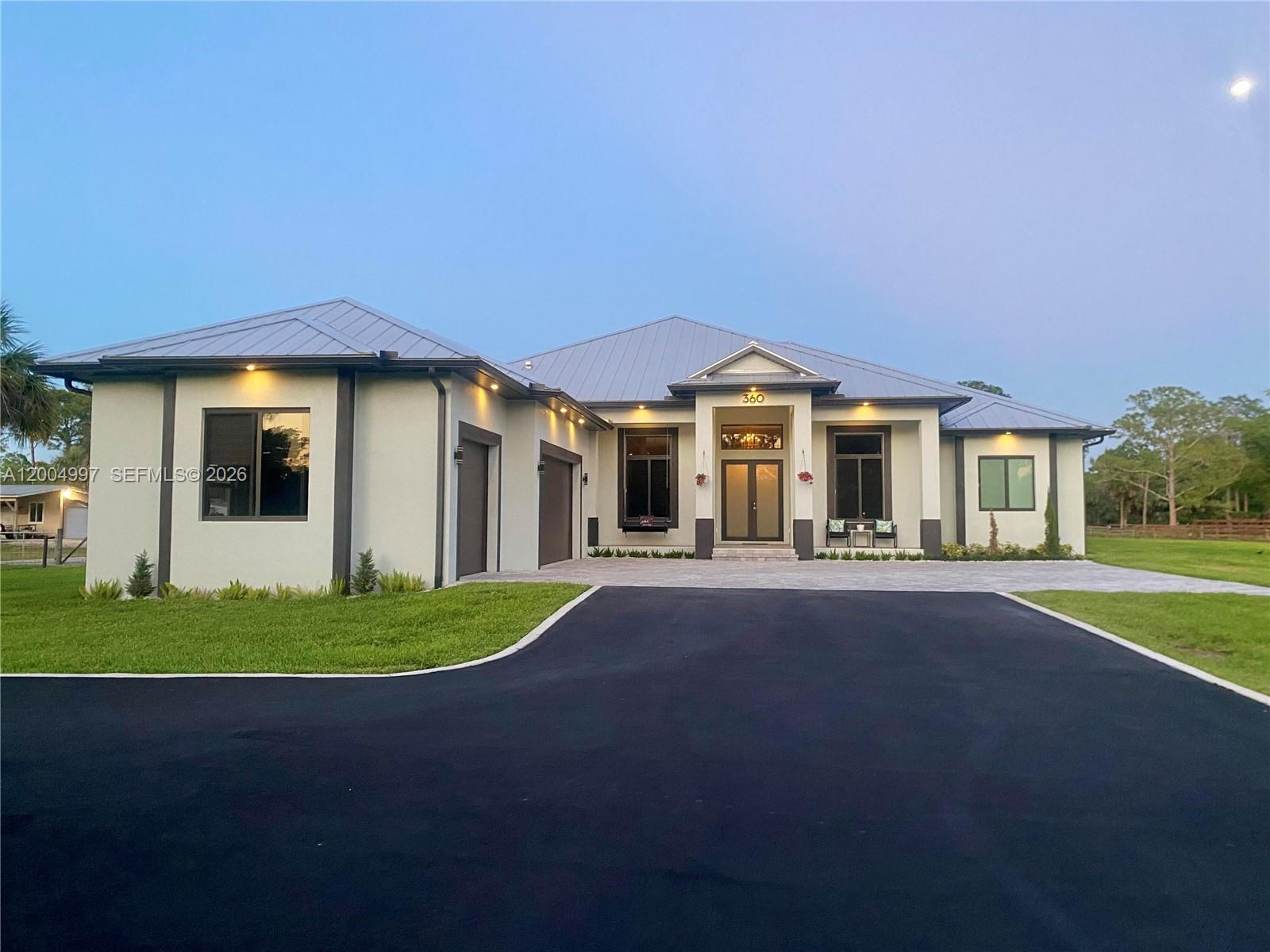 A modern single-story house with a metal roof, paved driveway, and attached garage — 360 13th St SW, Naples FL 34117, NAPLES, FL
