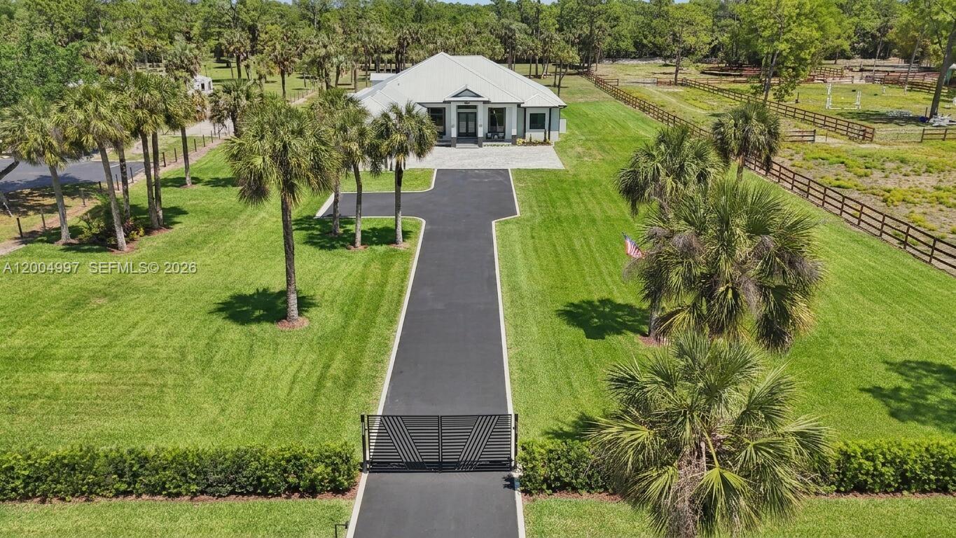 An aerial view shows a white house with a long driveway and gated entrance — 360 13th St SW, Naples FL 34117, NAPLES, FL