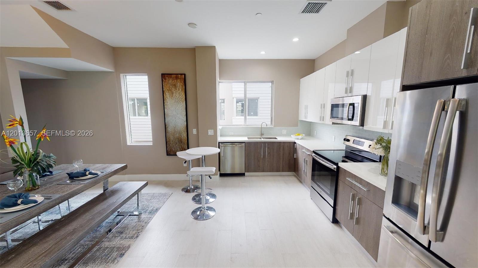 This kitchen features two-toned cabinetry, stainless steel appliances, and an adjacent dining area with benches — FORT LAUDERDALE, FL