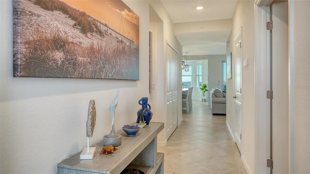 A hallway with a console table, coastal decor, and a view into an open living area — 12140 WELLEN GOLF STREET UNIT 306, VENICE, FL