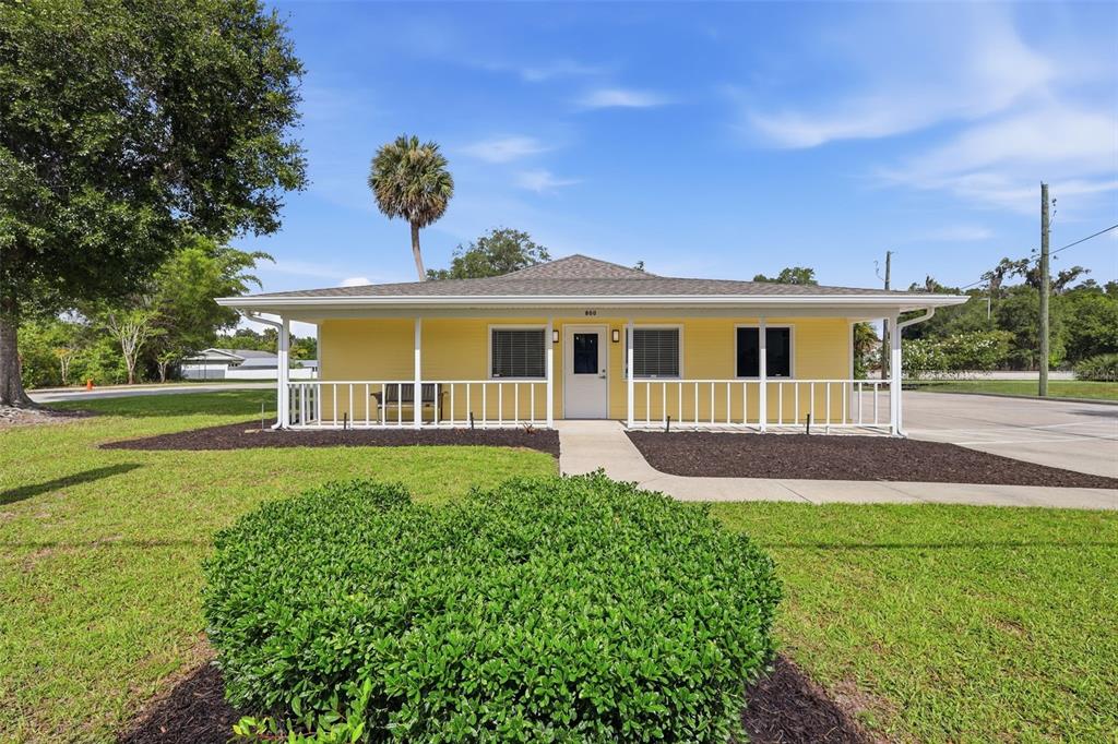 A yellow, single-story house with a front porch and a white railing stands outdoors — 800 N STONE STREET, DELAND, FL