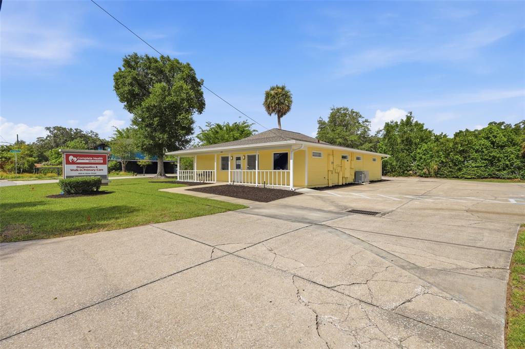 A yellow, single-story commercial building with a parking lot and a sign in the front — 800 N STONE STREET, DELAND, FL
