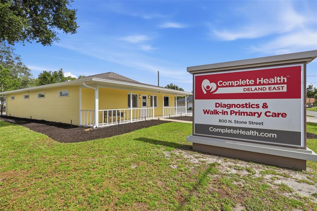 A yellow building with a white porch stands behind a large medical office sign — 800 N STONE STREET, DELAND, FL