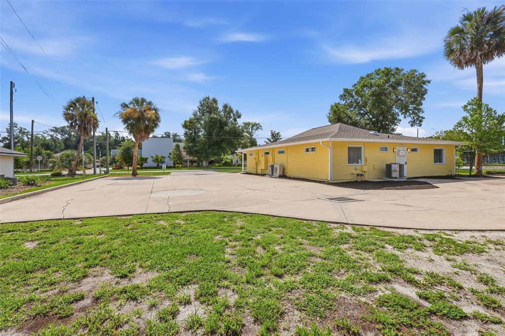 A yellow single-story building sits on a large concrete lot with palm trees — 800 N STONE STREET, DELAND, FL