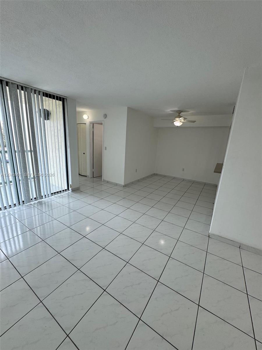 An empty room with white tiled floors, a ceiling fan, and vertical blinds on the window — 2055 SW 122nd Ave # 327, Miami FL 33175, MIAMI, FL