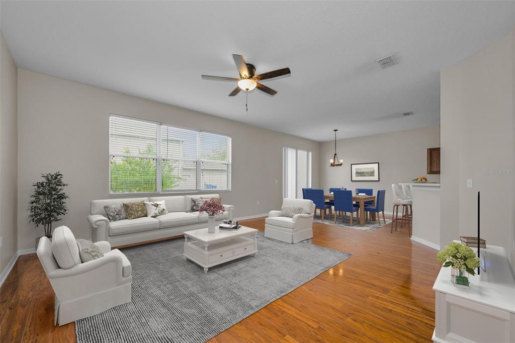 A living room with a white sofa, two armchairs, a coffee table, and a dining area — 17539 BALMAHA DRIVE, LAND O LAKES, FL
