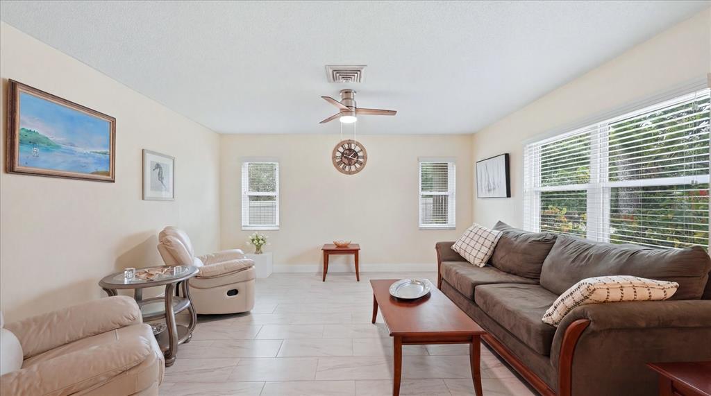 A living room features light tile flooring, a brown sofa, and two beige armchairs — 6233 ROCKEFELLER AVENUE, SARASOTA, FL