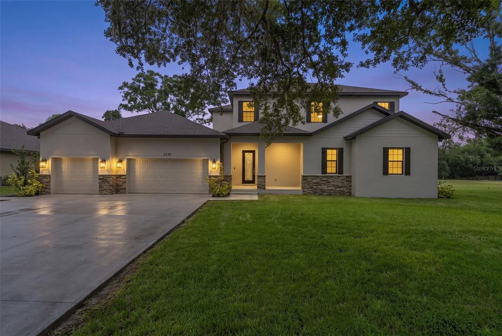 A two-story house with a three-car garage, stone accents, and a large front lawn — 2730 ROBERTSON TRAIL, LUTZ, FL