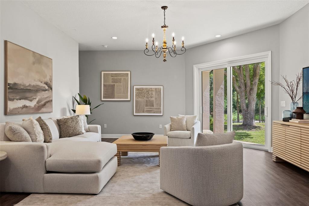 A living room features a sectional sofa, two armchairs, a chandelier, and sliding glass doors — 2730 ROBERTSON TRAIL, LUTZ, FL