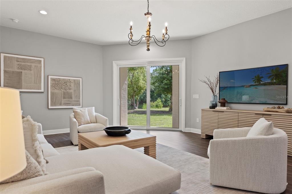 A living room features light gray walls, a chandelier, a sliding glass door, and neutral furniture — 2730 ROBERTSON TRAIL, LUTZ, FL