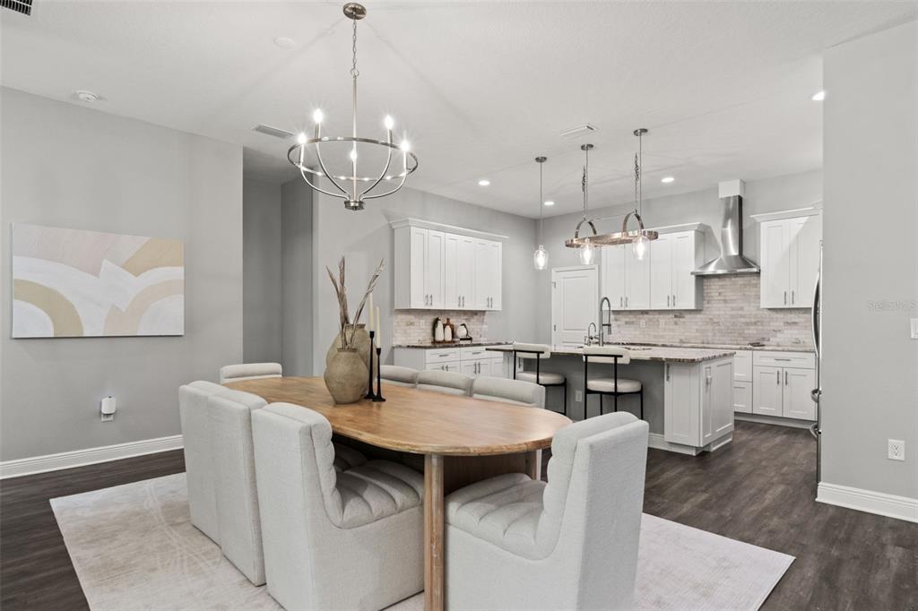 A dining area with a wooden table and upholstered chairs sits before an open kitchen — 2730 ROBERTSON TRAIL, LUTZ, FL