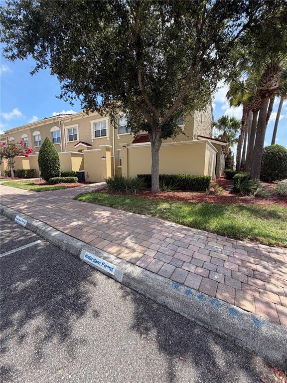 A paved walkway leads past a tan multi-story building with a landscaped yard and trees — 2404 BELLA VISTA DRIVE, DAVENPORT, FL