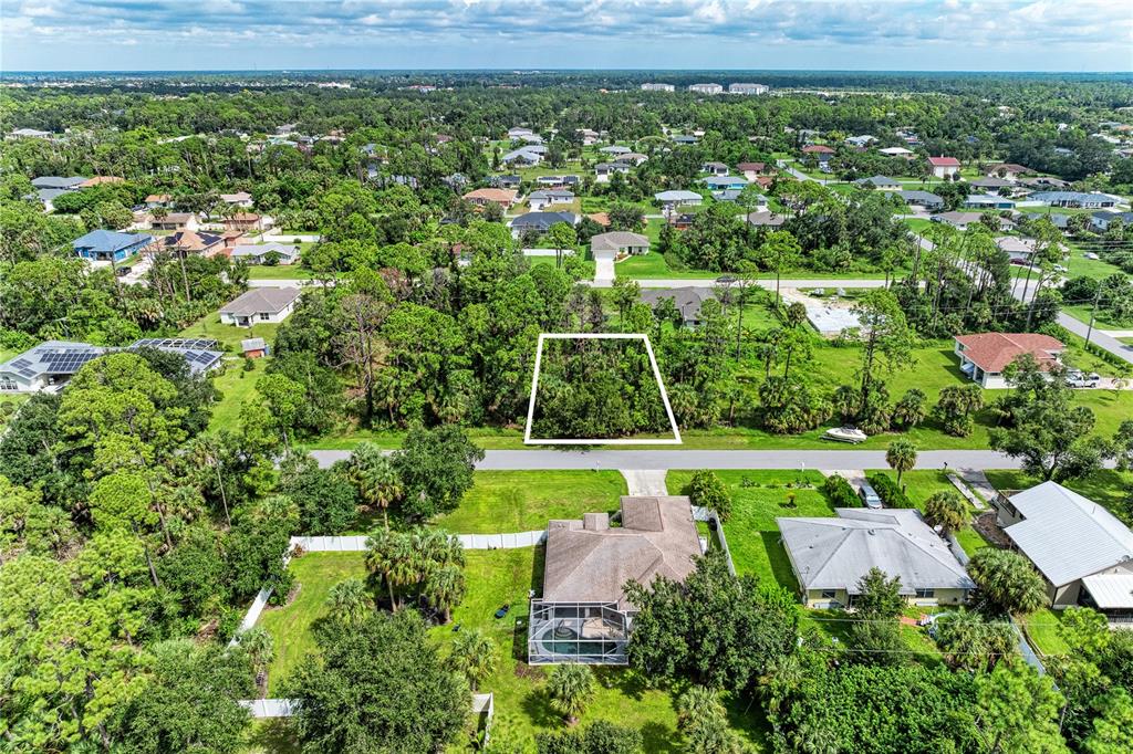 An aerial view shows a vacant, wooded residential lot outlined in white across a street — 15106 GULISTAN AVENUE, PORT CHARLOTTE, FL