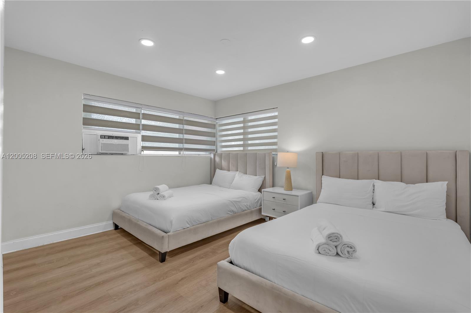 A bedroom features two upholstered beds, light wood flooring, and windows with horizontal blinds — 10006 E Bay Harbor Dr # 11, Bay Harbor Islands FL 33154, BAY HARBOR ISLANDS, FL