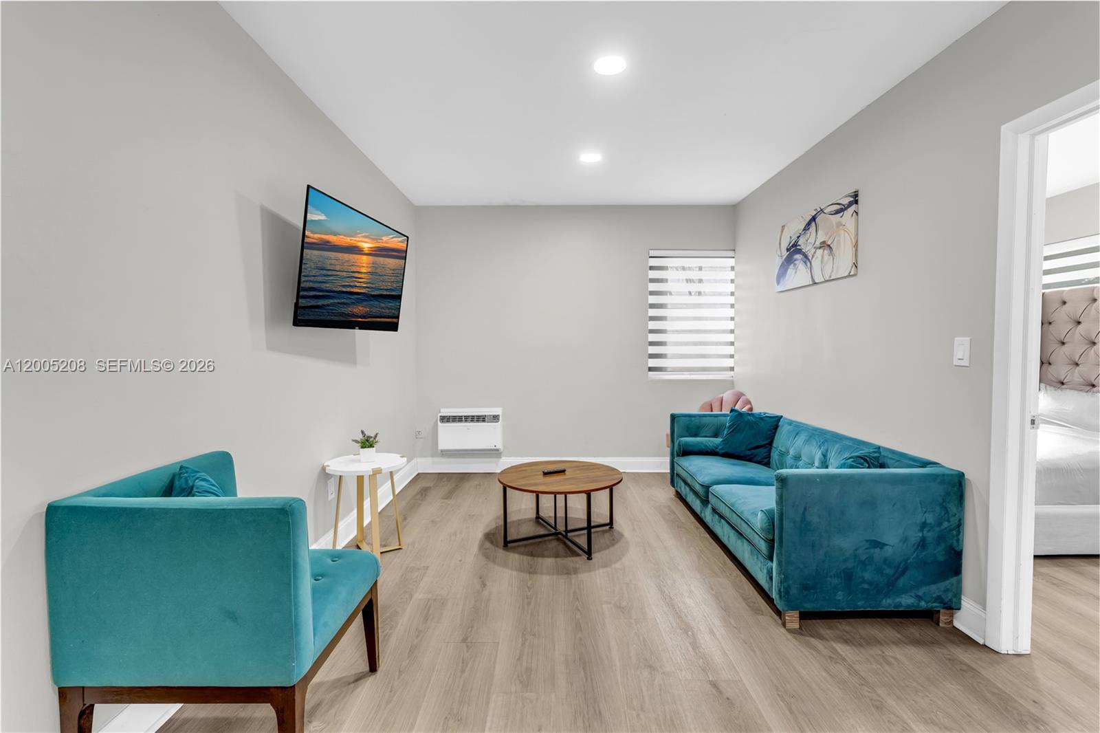 A living room features a teal sofa and armchair, a coffee table, and a wall-mounted television — 10006 E Bay Harbor Dr # 11, Bay Harbor Islands FL 33154, BAY HARBOR ISLANDS, FL