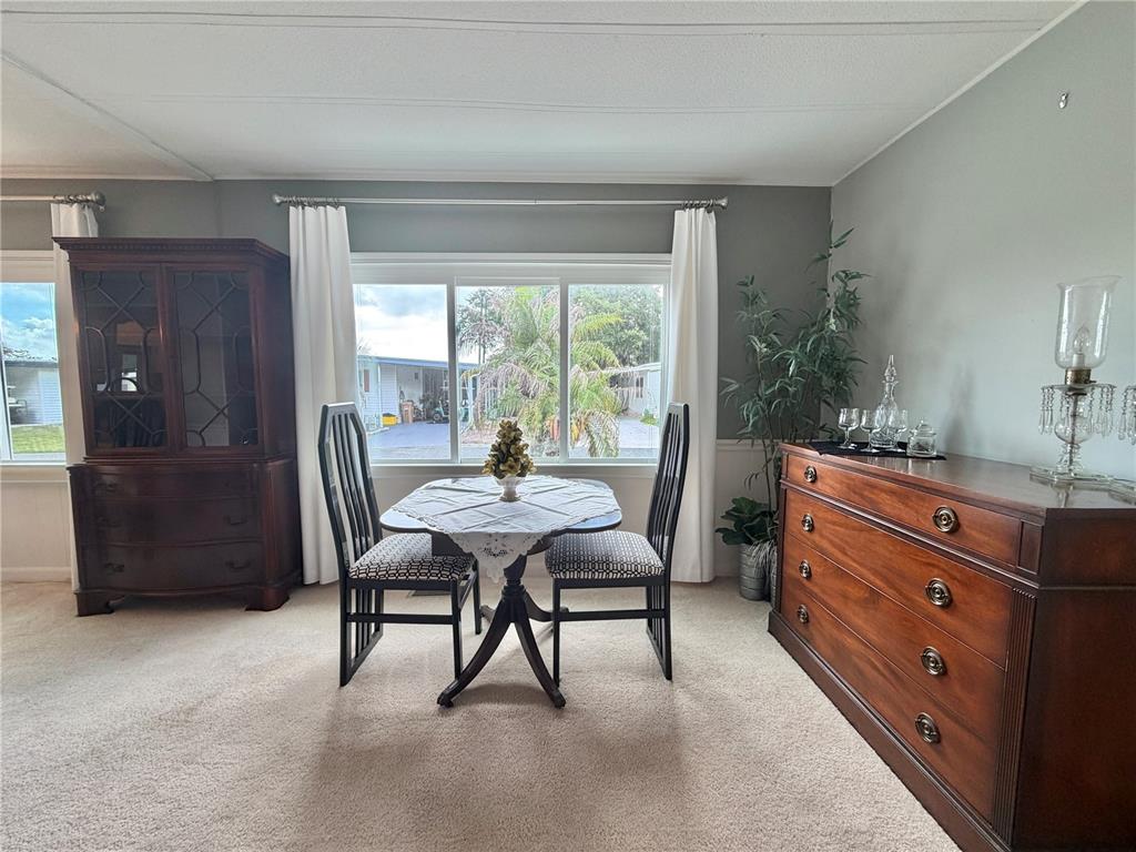 A dining area features a small table with two chairs between two wooden cabinets — 101 TAMARISK WAY, LEESBURG, FL