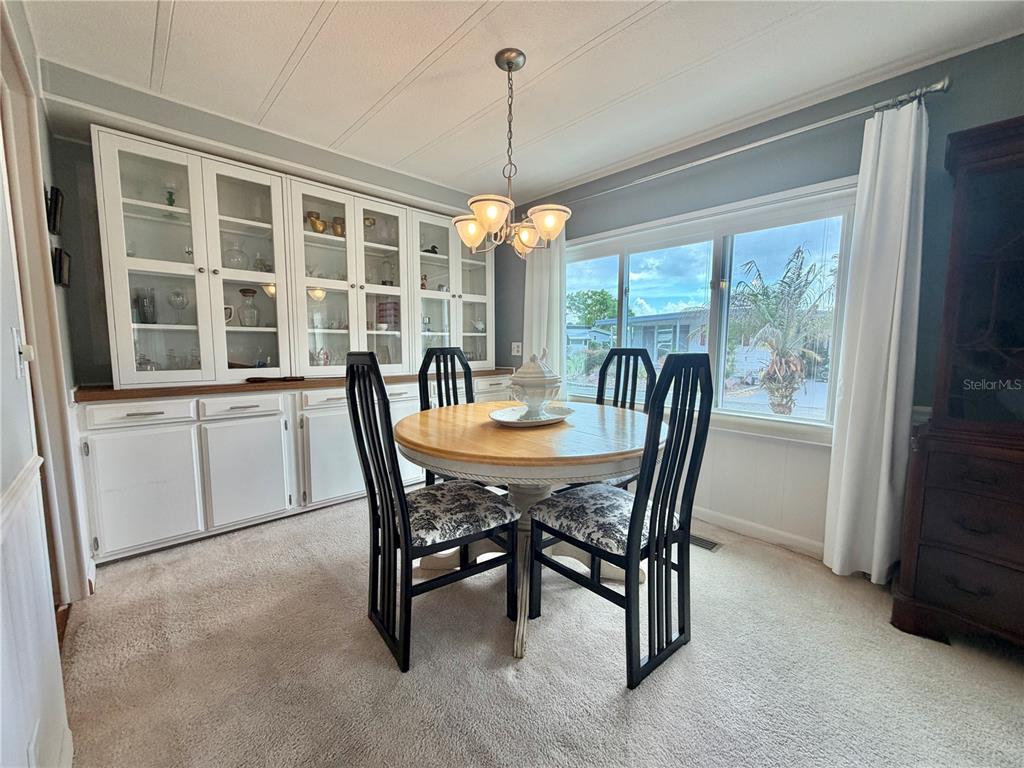 A dining room features a round wooden table, four black chairs, and a white hutch — 101 TAMARISK WAY, LEESBURG, FL