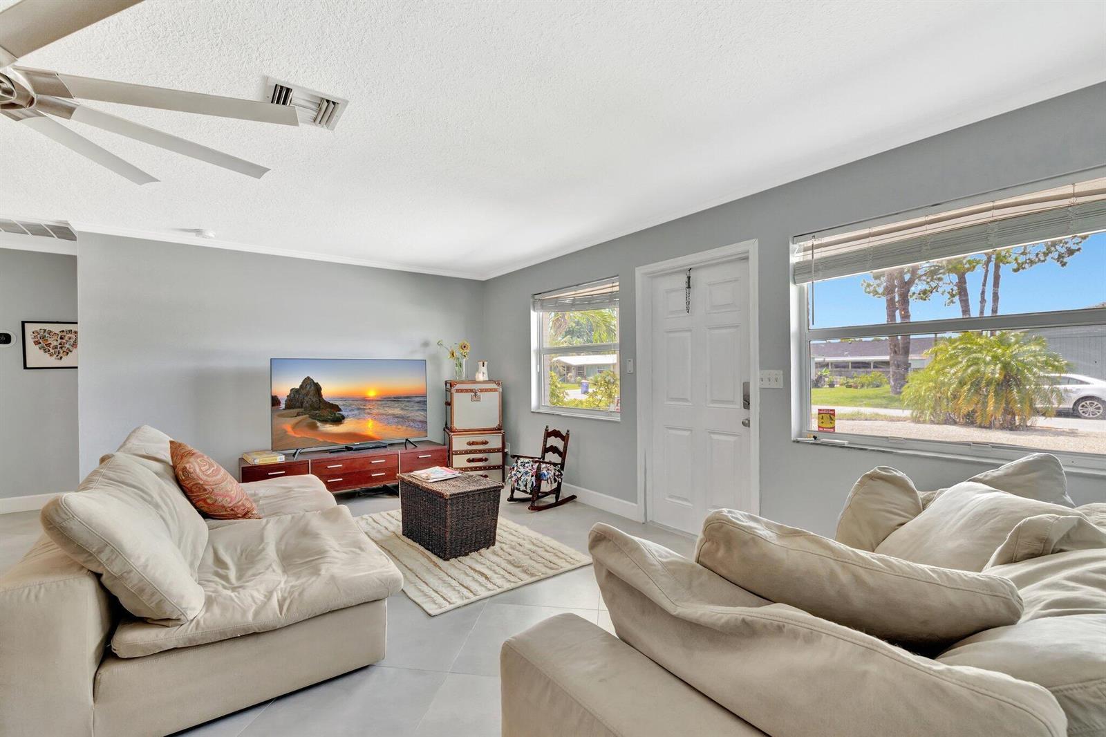 A living room features light gray walls, tile flooring, two beige sofas, and a television — 1894 SE Lafayette Street, Stuart FL 34997, STUART, FL