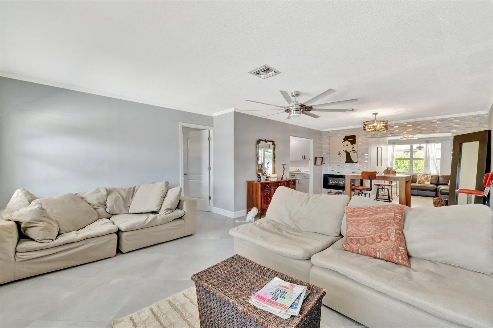 A living room with light gray walls, tile flooring, two beige sectionals, and a dining area — 1894 SE Lafayette Street, Stuart FL 34997, STUART, FL
