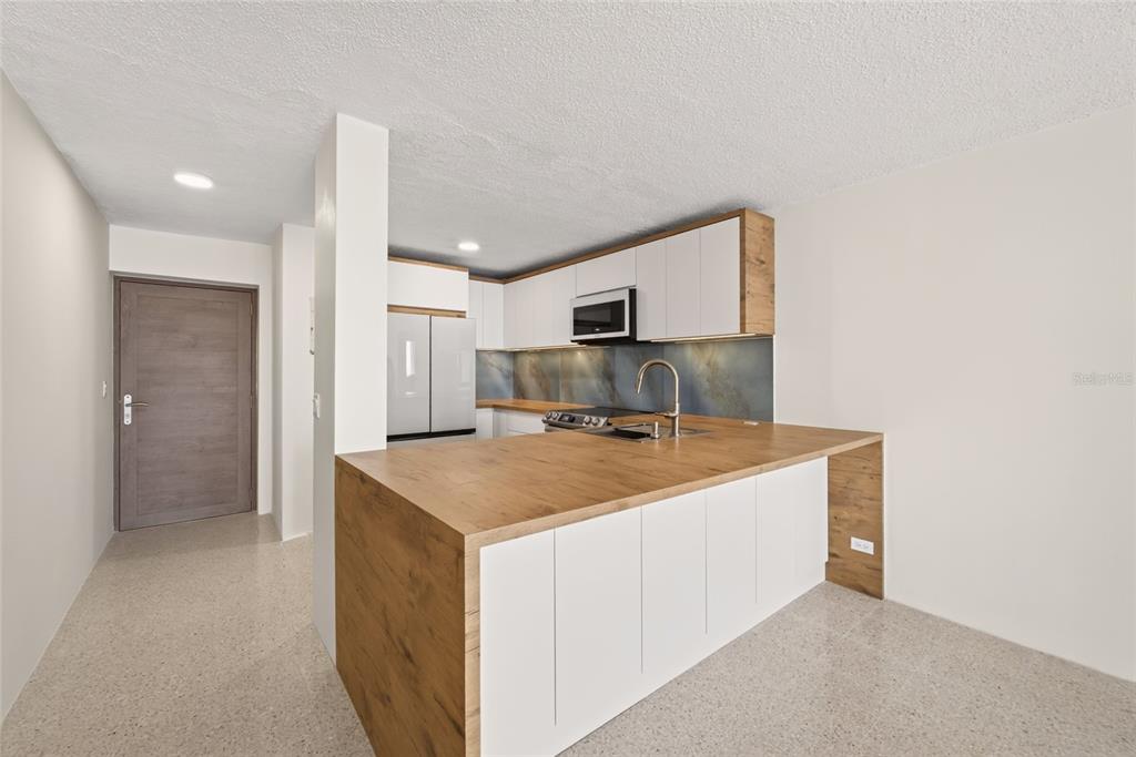 An empty living room with terrazzo floors and a balcony door overlooking the ocean — 3409 AVE. ISLA VERDE UNIT 704, CAROLINA, PR