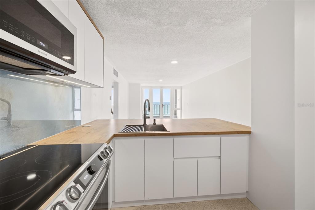 A modern kitchen features white cabinets, wood countertops, a stainless steel stove, and a backsplash — 3409 AVE. ISLA VERDE UNIT 704, CAROLINA, PR